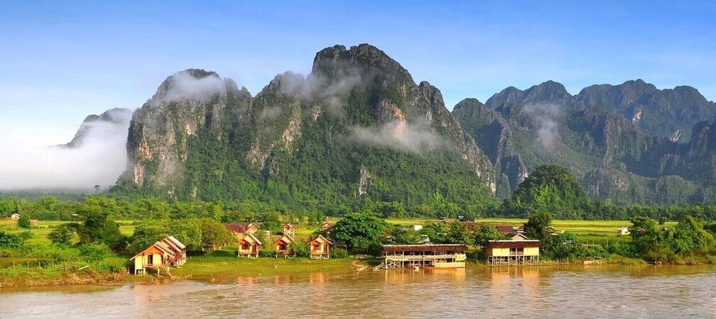 Village Lao niché entre les rives de la rivière Nam Song et les pitons rocheux de la région de Vang Vieng